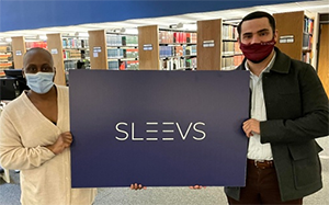 students hold up a sign display the Sleevs apparel logo
